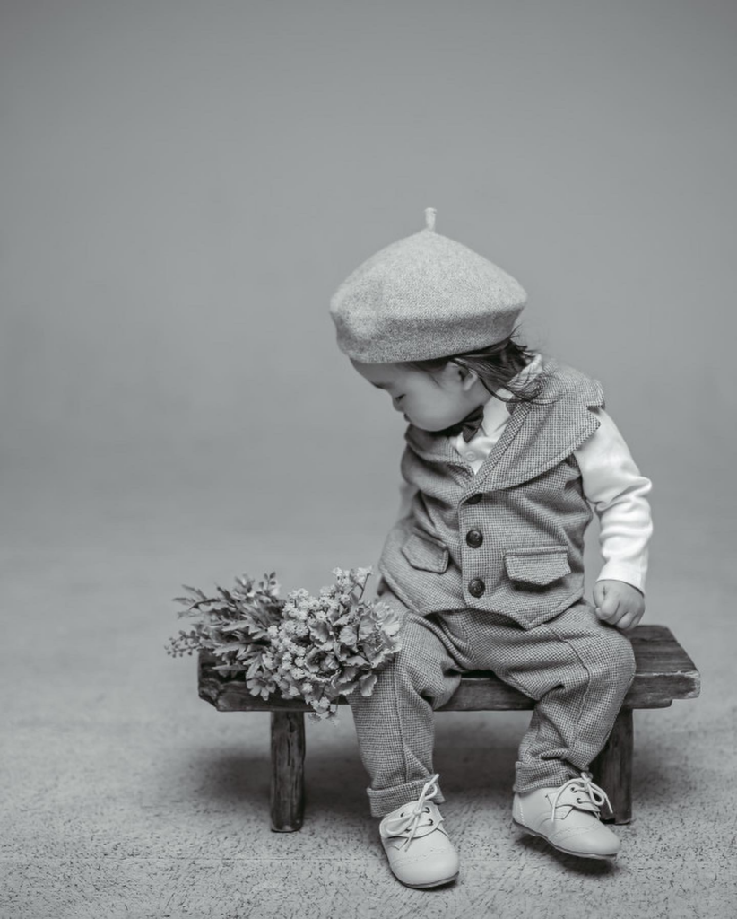 A smiling Korean baby celebrating their first birthday in a minimalist modern studio setting, capturing a "growth album" milestone.
